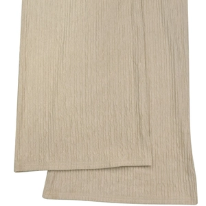 Close-up detail of light beige crinkled fabric texture on women's stylish halter-neck trousers set