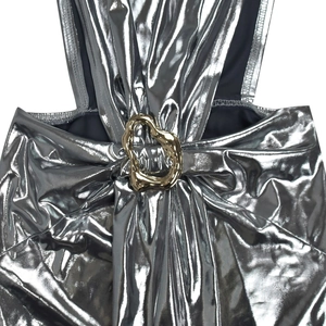 Detailed close-up of metallic silver dress featuring a decorative gold heart buckle