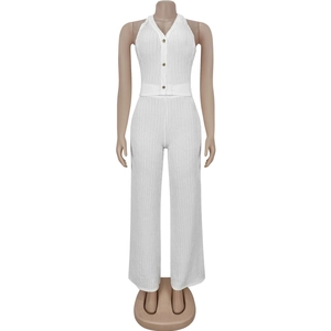 Detail of white halter cardigan with gold buttons and pleated wide-leg trousers fabric