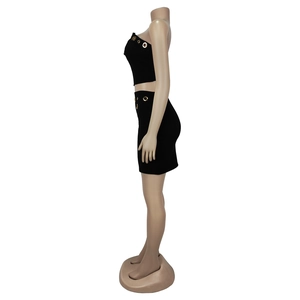 Detail view of black bodycon two-piece set featuring gold metal eyelets on top and skirt