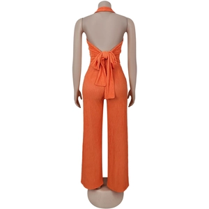 Detail of orange halter jumpsuit with tie-back bow and pleated vertical texture