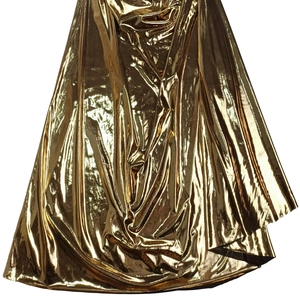 Makro-Detail des hochglänzenden goldenen Metallgewebes mit eleganten Falten am Kleid