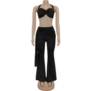 Détail d'un ensemble deux pièces noir avec haut dos nu torsadé et pantalon évasé à ceinture