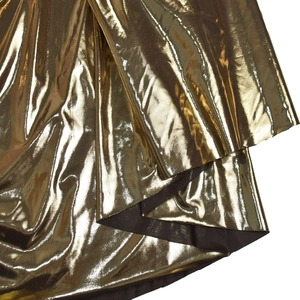 Detail aus metallisch goldfarbenem Faltenstoff mit dunklem Futter für Abendkleider