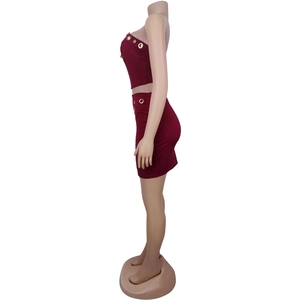 Detail of wine red two-piece set featuring golden eyelet buttons on the side of the skirt