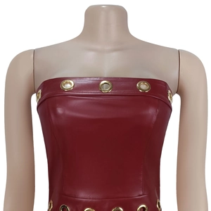 Dettaglio di un abito in pelle PU rossa con occhielli metallici dorati sulla scollatura