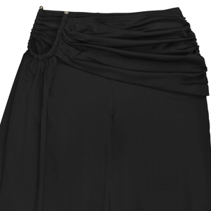 Détail du pantalon noir soyeux avec couches plissées et anneau métallique à la taille