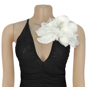Close-up of a large white fabric flower accessory on a black pleated deep V-neck garment