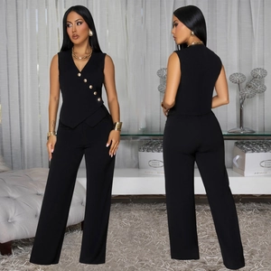 Détail d'un haut noir à col en V avec boutons dorés et pantalon large à taille haute