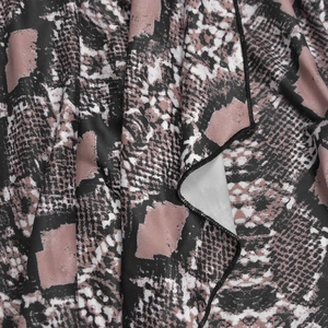 Gros plan sur tissu imprimé serpent rose avec coutures fines et texture douce