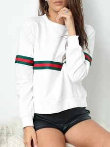 Détail du sweat-shirt blanc avec rubans rayés rouge et vert emblématiques sur les manches