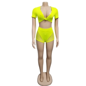 Detail of neon yellow two-piece set with tie-up crop top and mesh side shorts