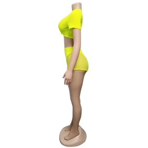 Detail view of neon yellow two-piece set featuring crop top and mesh overlay shorts