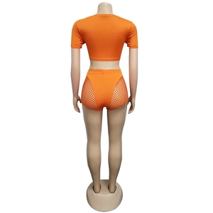 Rear view of orange crop top and high-waisted shorts with fishnet side panels
