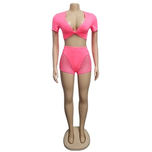 Detail of neon pink two-piece set featuring twist knot crop top and mesh panel shorts