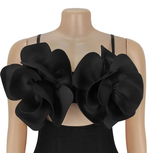Detail of 3D handcrafted satin flowers and delicate spaghetti straps on a black dress