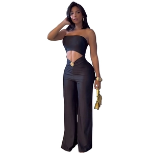 Detail of high-waist black wide-leg pants featuring gold bow buckle and side cut-outs