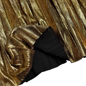 Detail of elegant gold metallic pleated fabric with fine vertical texture and black lining