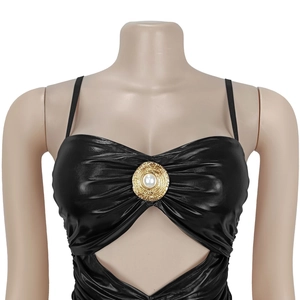 Detail of black shiny camisole featuring front pleats and gold pearl metal ornament