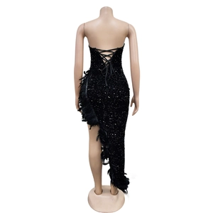 Détail d'une robe noire à paillettes avec bordure en plumes et dos lacé ajusté