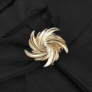 Detail of a golden spiral brooch with textured metal finish on black ribbed knit fabric
