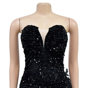 Détail de robe noire à paillettes avec décolleté en V profond et empiècements en mesh