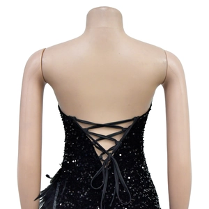Détail du laçage au dos d'une robe noire à paillettes avec des finitions en plumes