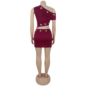 Détail de l'ensemble deux pièces bordeaux avec œillets dorés et texture en daim élégante