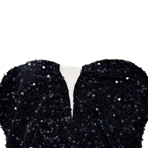 Gros plan détaillé des paillettes noires brillantes sur l'encolure en cœur d'une robe