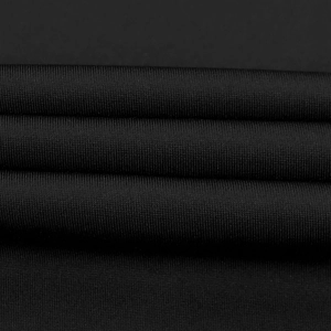 Macro shot of high-density black knitted fabric showing fine texture and soft flexibility