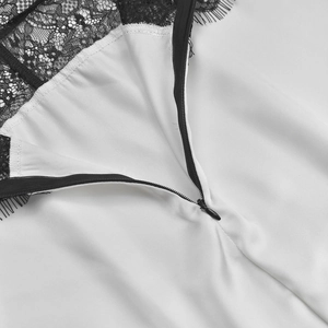 Detail of hidden back zipper with delicate black eyelash lace trim on a white dress