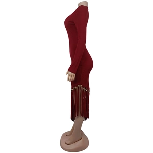 Dettaglio dell'abito in maglia bordeaux con orlo a frange e perline dorate