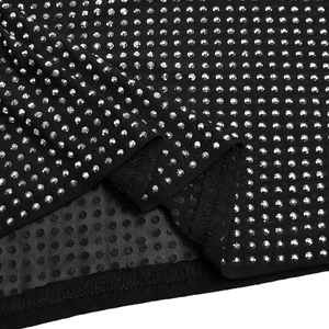 Macro detail of sparkling silver rhinestones on black mesh fabric for women's dress