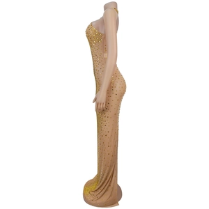Détail d'une robe maxi moulante en mesh avec strass dorés scintillants sur tissu nude
