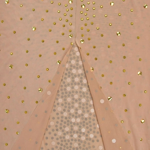 Détail du tissu en maille avec strass dorés et superposition transparente d'une robe