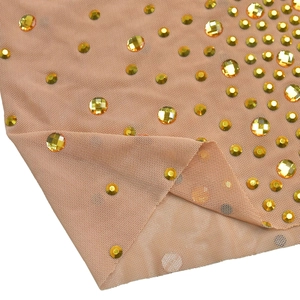 Gros plan sur un tissu en résille chair orné de strass ambrés dorés aux multiples facettes