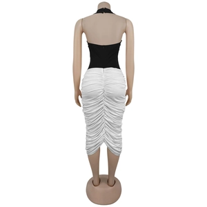 Detail view of the ruched white skirt and invisible back zipper on a halter dress