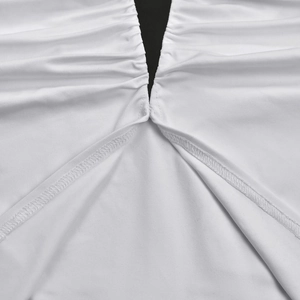 Detailed close-up of white dress fabric with fine pleats and black contrast stitching