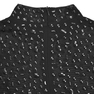 Dettaglio vestito in rete nera a collo alto con decorazioni in strass e cerniera posteriore