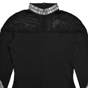 Détail du patchwork en tulle et des strass argentés brillants sur une robe noire à col haut