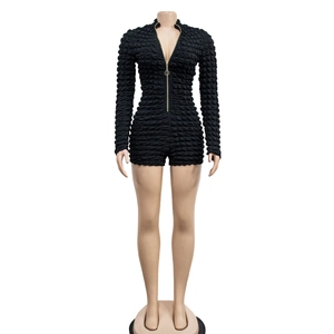 Detail of black long sleeve romper featuring honeycomb bubble texture and gold front zipper