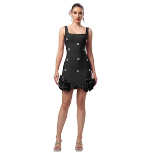 Détails d'une mini robe noire élégante avec fleurs en strass et ourlet à volants plissés
