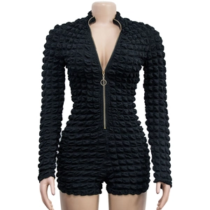 Close-up of black long sleeve romper with textured fabric and golden ring zipper