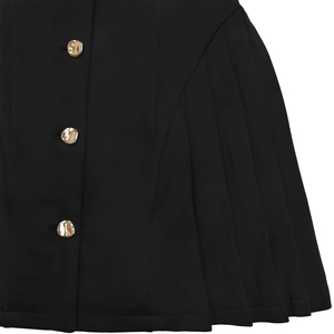 Detail of elegant black dress featuring gold irregular buttons and vertical pleated fabric