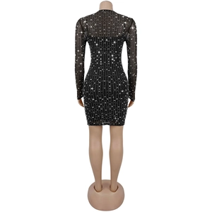 Dettaglio dell'abito corto in mesh nero con strass argentati e maniche lunghe