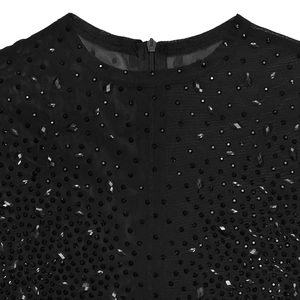 Dettaglio in rete nera con strass e paillettes cuciti a mano su abito trasparente