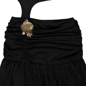 Detail of ruched black dress fabric featuring a golden seashell and starfish pendant