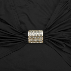 Macro shot of gold buckle with sparkling crystals on black backless silk outfit detail
