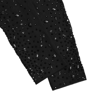 Dettaglio del tessuto a rete trasparente con strass neri scintillanti sul vestito