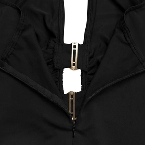 Détail du tissu en maille noire avec boucles métalliques dorées et fermeture éclair invisible